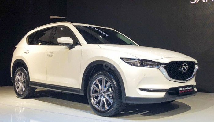 Chiếc xe Mazda 3 màu đỏ đang di chuyển trên đường, thể hiện thiết kế Kodo ấn tượng của hãng xe Nhật Bản
