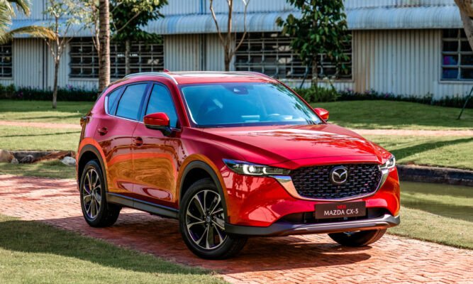 Một chiếc Mazda màu đỏ đang di chuyển trên đường