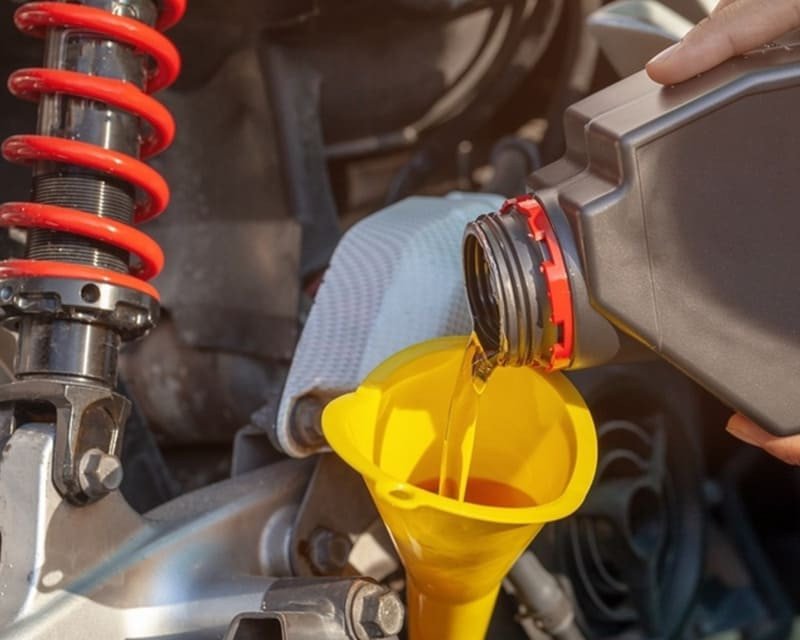 Dầu nhớt đang được đổ vào động cơ xe máy, minh họa tầm quan trọng của việc bôi trơn và bảo vệ hệ thống