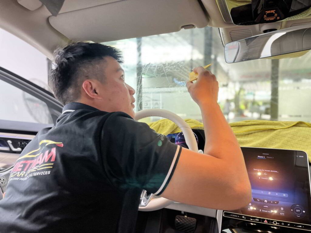 Kỹ thuật viên đang dán phim cách nhiệt cho cửa kính xe ô tô
