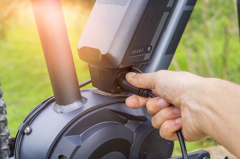 Người dùng đang cắm sạc cho pin xe đạp điện theo đúng quy trình hướng dẫn