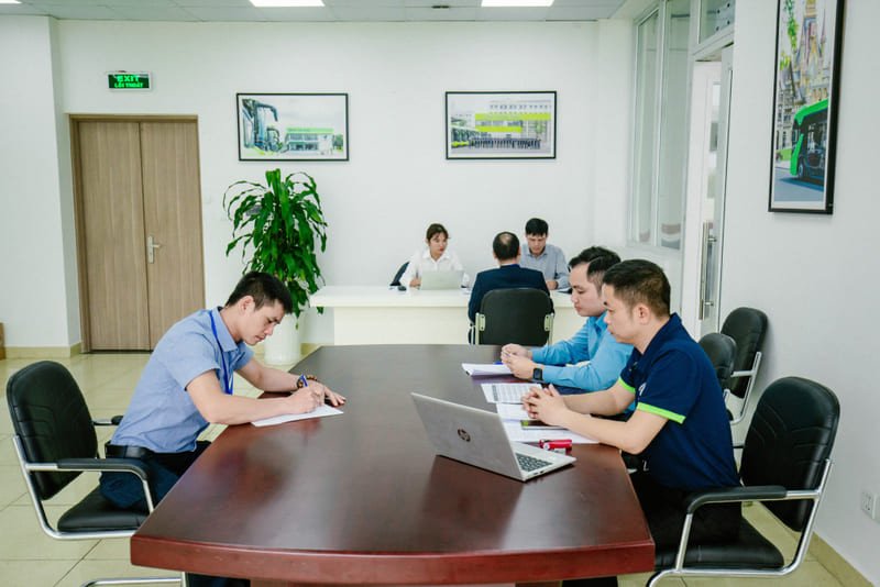 Người lái xe chuyên nghiệp đang đứng cạnh ô tô, thể hiện sự chỉn chu và sẵn sàng làm việc.