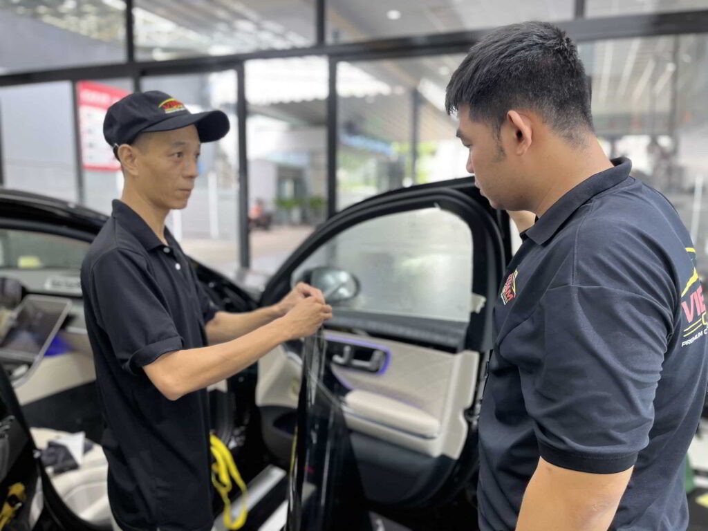 Người thợ đang thi công dán phim cách nhiệt ô tô trên kính xe