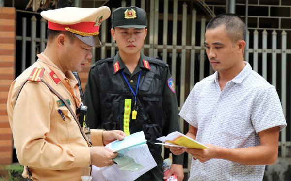 Tài xế xe hơi đang được kiểm tra giấy tờ bởi cảnh sát giao thông tại một chốt kiểm soát giao thông trên đường.