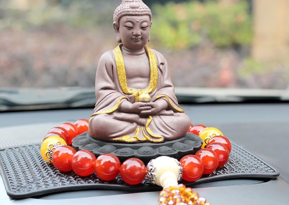 Tượng Phật Di Lặc bằng gỗ đặt trên taplo xe ô tô, mang ý nghĩa bình an và tài lộc khi trang trí nội thất xe hơi.