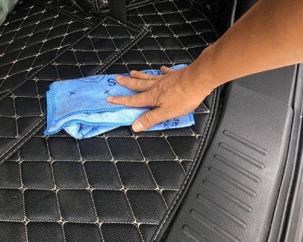 Vệ sinh thảm lót sàn xe bằng bàn chải và dung dịch làm sạch, đảm bảo không gian xe luôn sạch sẽ khi dọn nội thất ô tô.